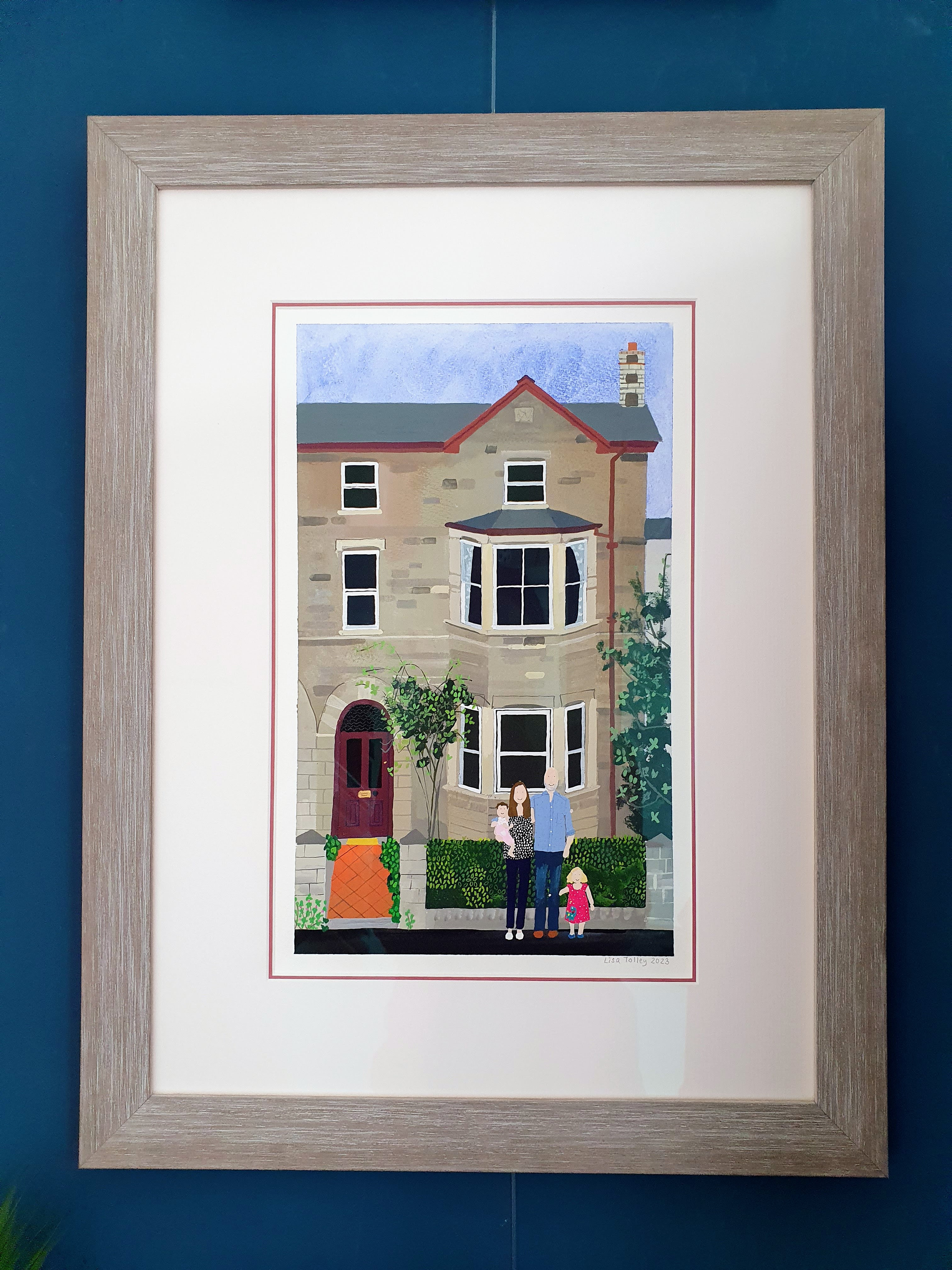 Hand-painted family-and-house portrait by Lisa Telling, framed in limed oak with a deep white mount and thin red bevel
