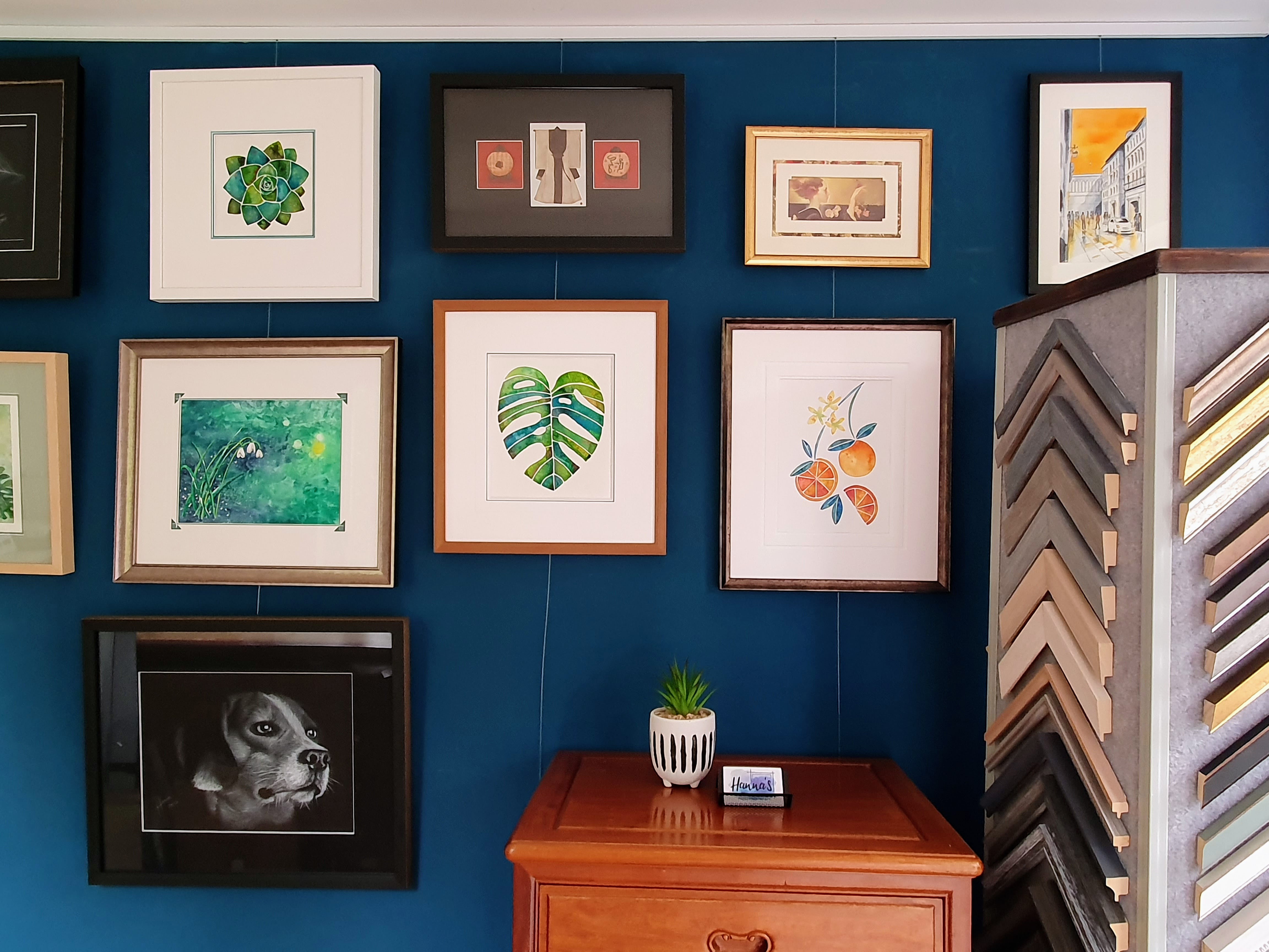 Detail of the studio wall: mixed mouldings, oak chest of drawers, the corner of the moulding chevron rack visible at right.
